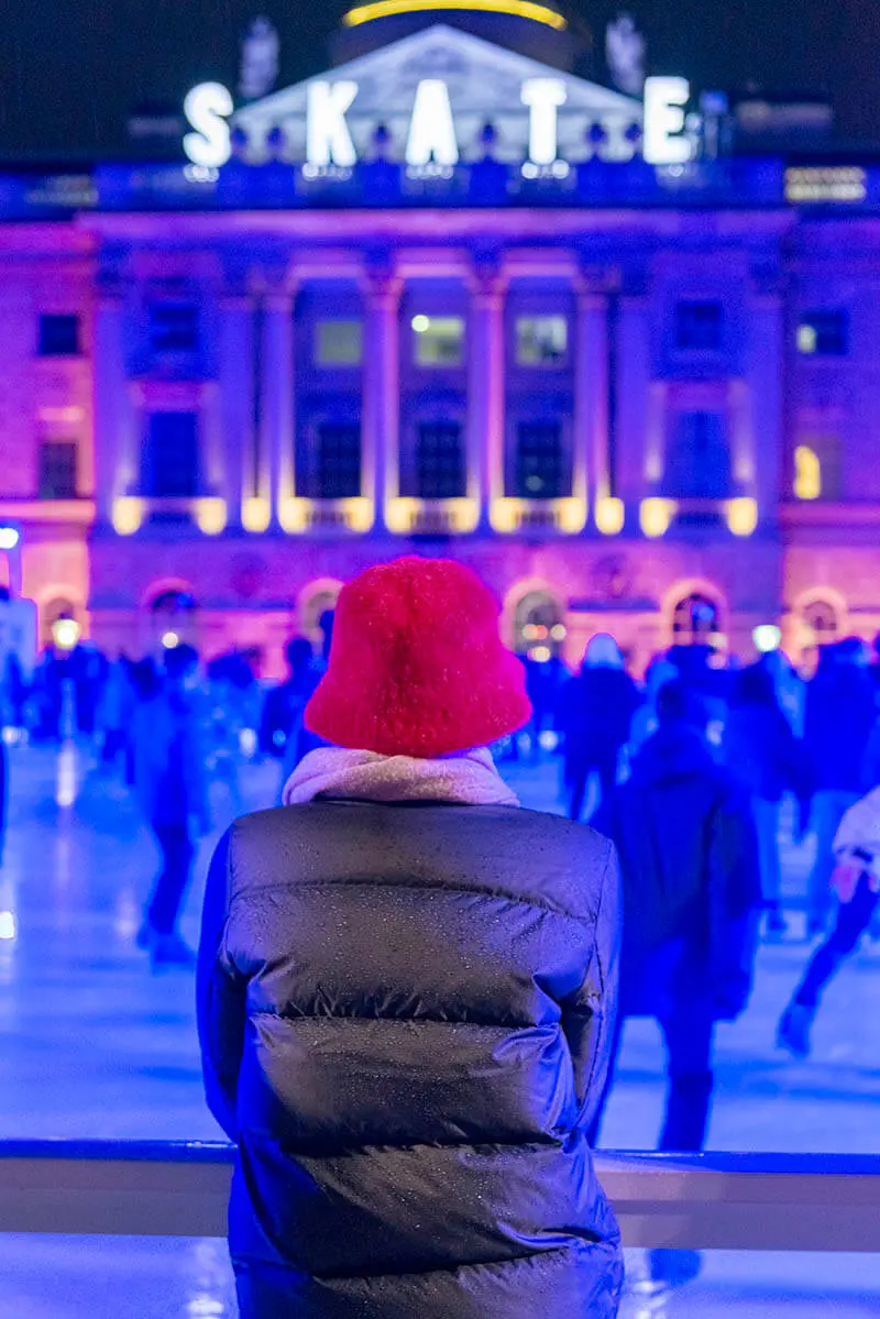 Woman Watching Skaters  at The Christmas Ice Skating Rink at Somerset House in London