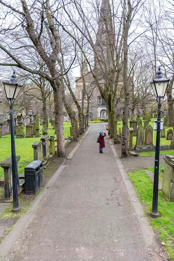 Woman Taking Photo in St Cubert Cemetery Edinburgh 